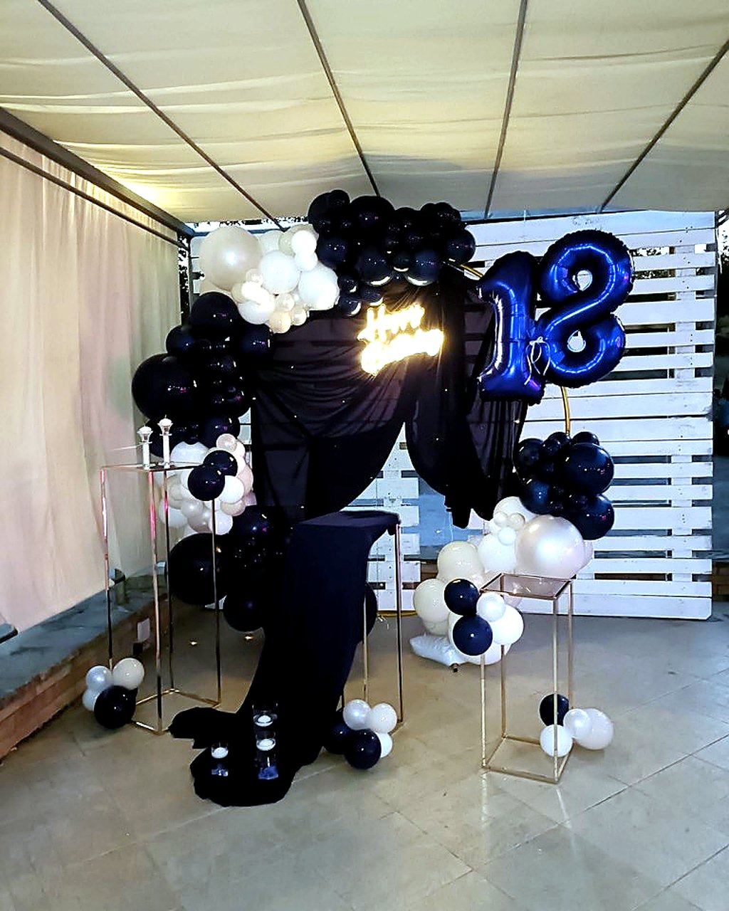 Sweet table e allestimento per compleanno 18 anni con palloncini blu e bianco, insegna luminosa Happy Birthday e dettagli oro